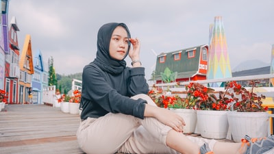 女人在灰色头巾和灰色长袍坐在替补席上白色混凝土白天
